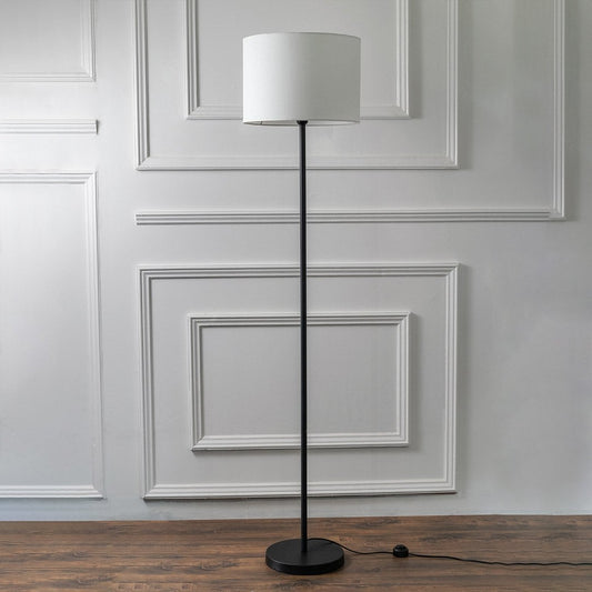 Modern floor lamp with black stand and white fabric lampshade on a plain white background – minimalist home lighting