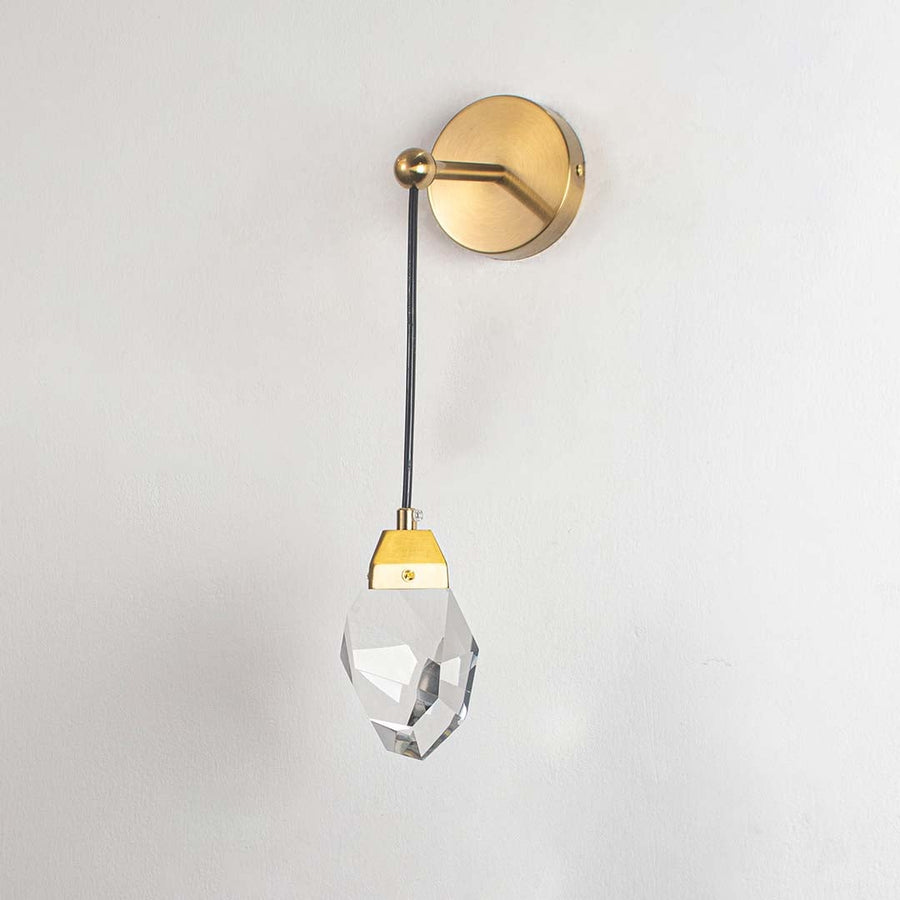 Gold wall light with crystal detail switched off on white background for minimalist modern bedroom wall lighting.