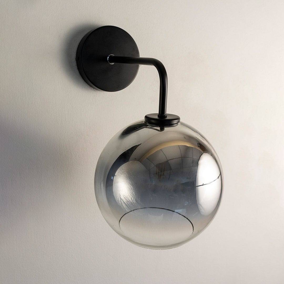 Smoky glass globe wall light with black metal arm displayed on white background ideal for modern home interiors.