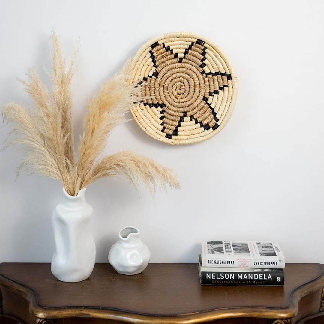 Beige handwoven sabai grass wall basket styled above console table bringing soft natural tones and coastal inspired texture to living room walls.