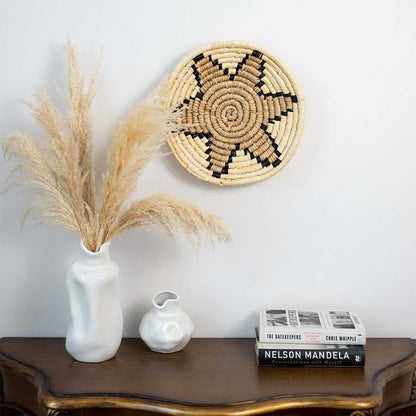 Beige handwoven sabai grass wall basket styled above console table bringing soft natural tones and coastal inspired texture to living room walls.