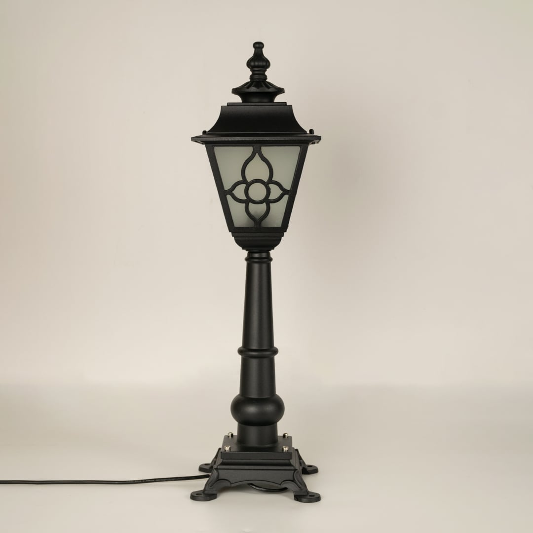 A vintage style outdoor pillar lamp shown on a white background with the light off highlighting its frosted glass panels curved lantern top and detailed sculpted base.