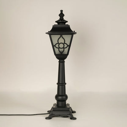 A vintage style outdoor pillar lamp shown on a white background with the light off highlighting its frosted glass panels curved lantern top and detailed sculpted base.