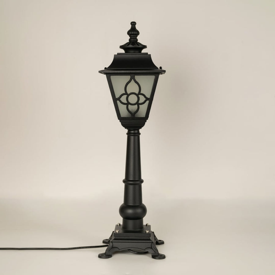 A vintage style outdoor pillar lamp shown on a white background with the light off highlighting its frosted glass panels curved lantern top and detailed sculpted base.