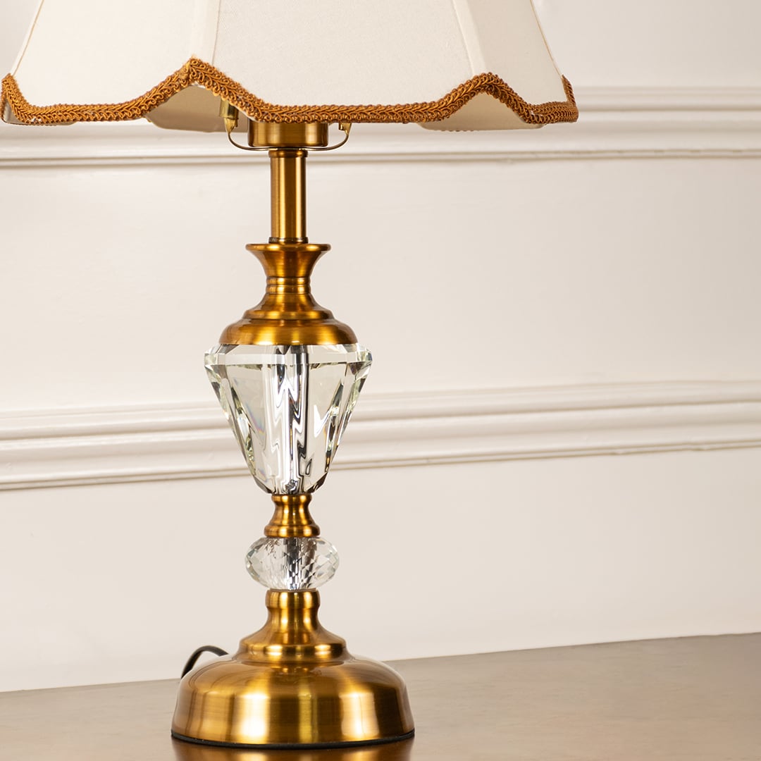 Closeup of gold and crystal base with cream fabric shade highlighting fine detailing and craftsmanship table lamp.