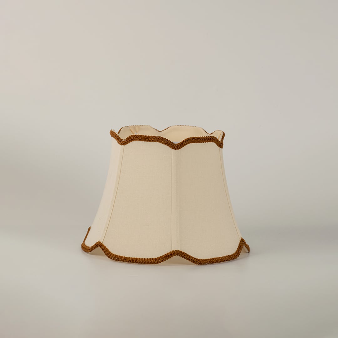 Cream fabric lamp shade with decorative trim shown alone on white background replacement shade for table lamp.