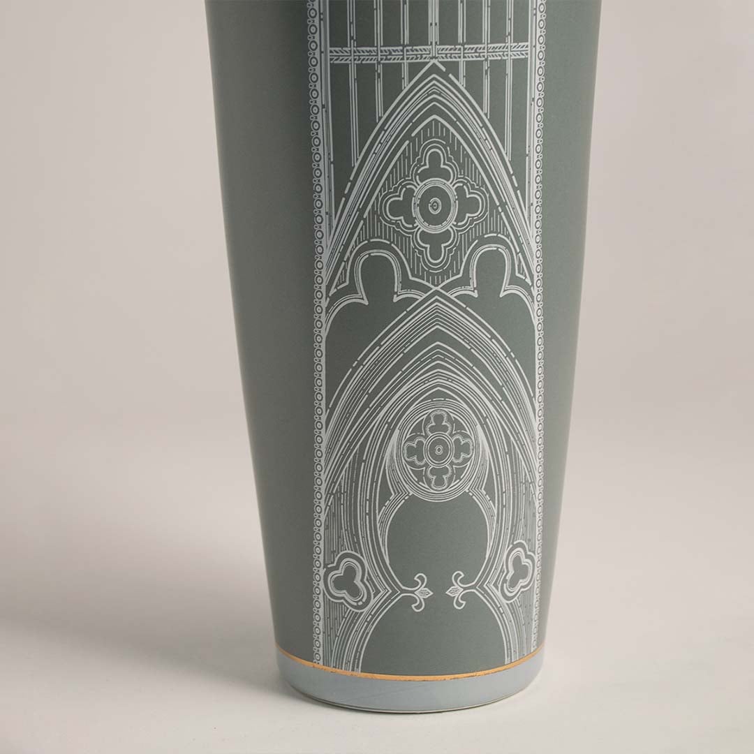 Detailed closeup of ceramic jar in green with golden lid and fine white artwork for stylish luxury decoration.