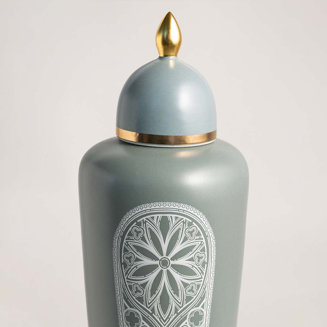 Light blue ceramic decorative jar with floral embossed design and gold lid for contemporary tabletop styling and decor.
