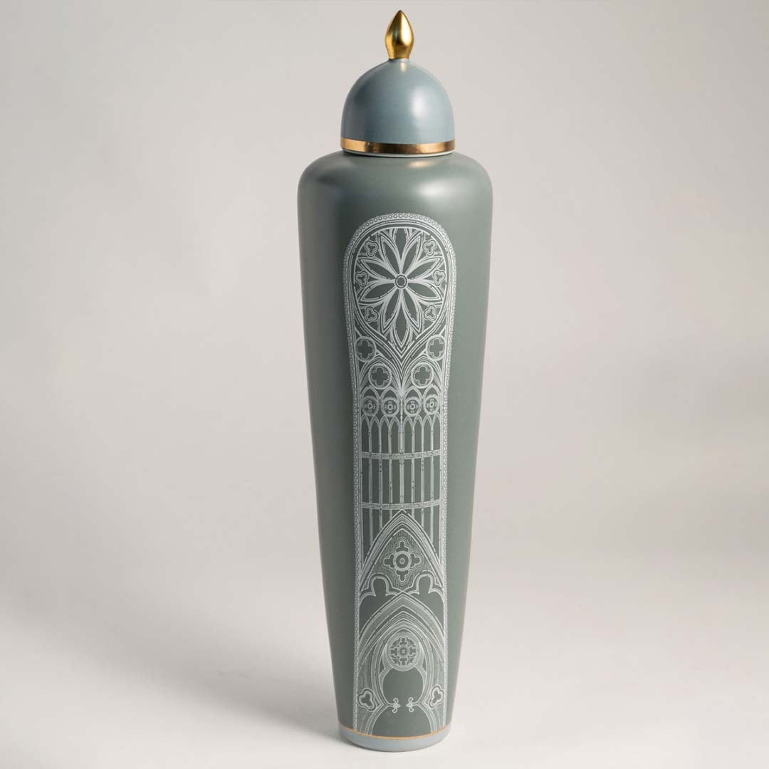 Elegant matte green ceramic jar with golden detailing and white artistic pattern on white background for interiors.