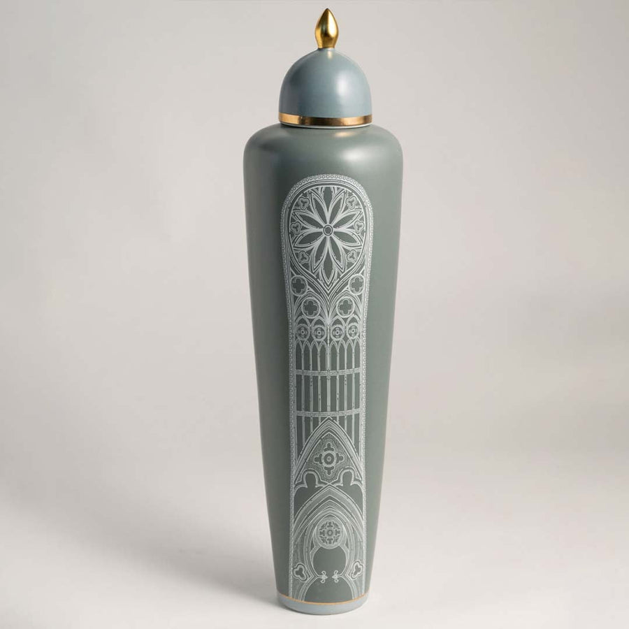 Elegant matte green ceramic jar with golden detailing and white artistic pattern on white background for interiors.