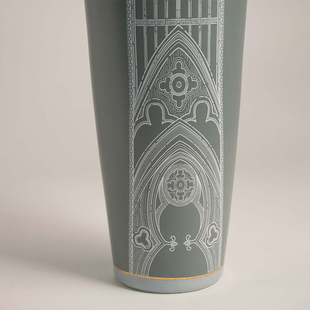 Detailed closeup of green ceramic jar with golden finial showcasing fine white patterned artwork for stylish decor.