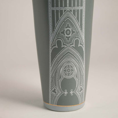 Detailed closeup of green ceramic jar with golden finial showcasing fine white patterned artwork for stylish decor.