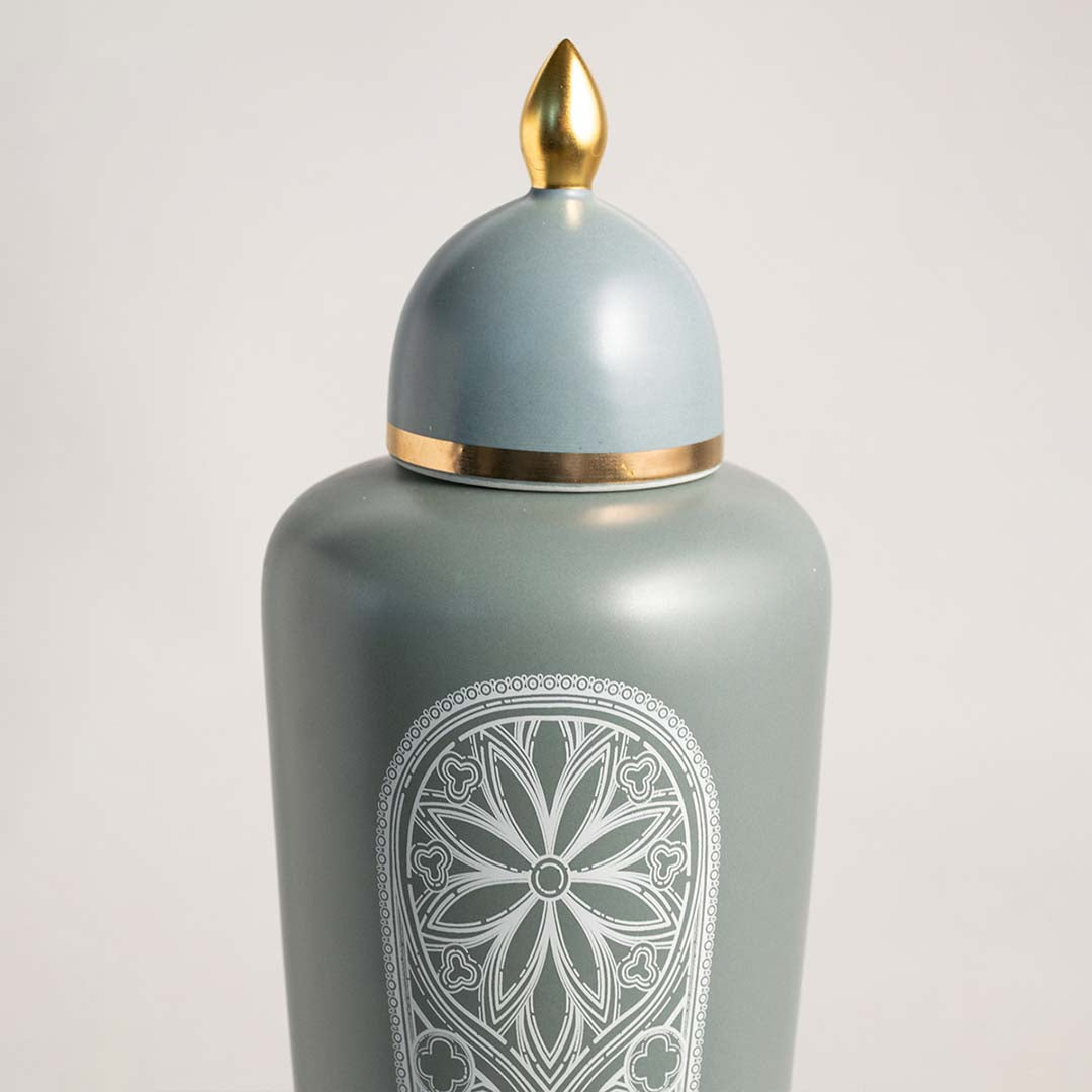 Light blue ceramic decorative jar with embossed floral pattern and gold finial for luxury shelf styling and home decor.