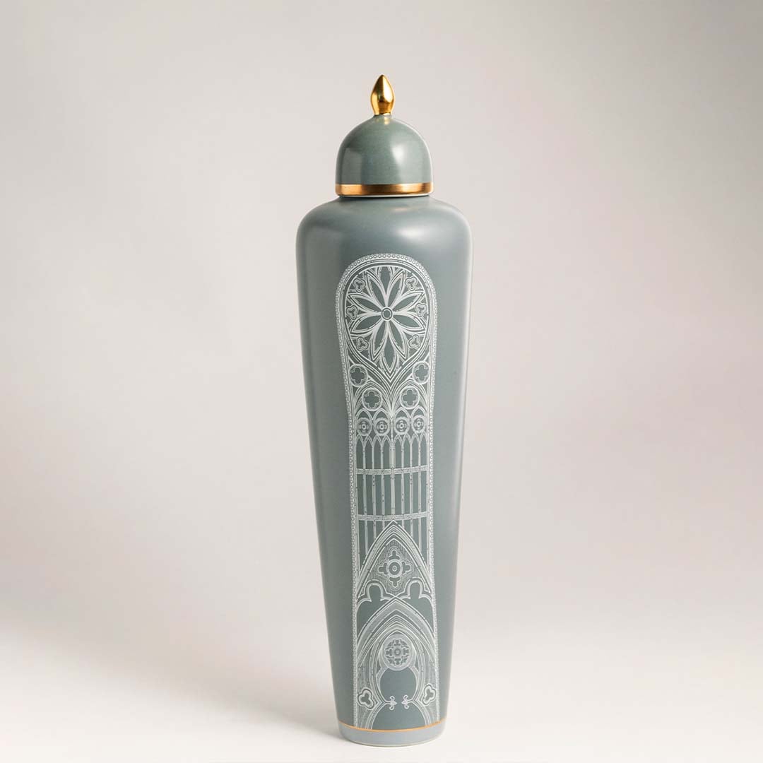 Elegant green ceramic jar with white artistic detailing and golden lid on white background for modern interiors.