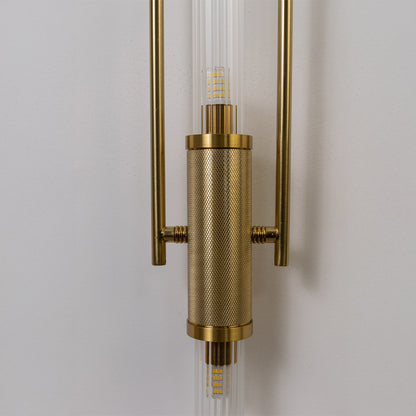 Closeup wall light in gold metal finish with cylindrical detail for bedroom or living decor lighting white background.