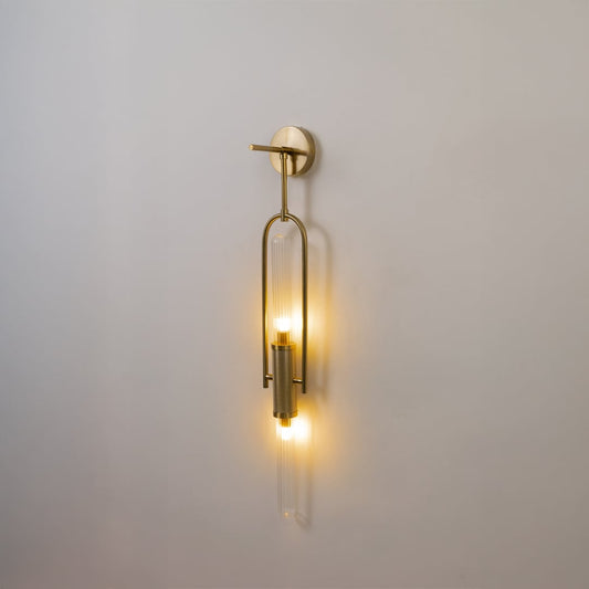 Gold metal wall light with ribbed glass tube glowing softly on white background for elegant modern wall decor.