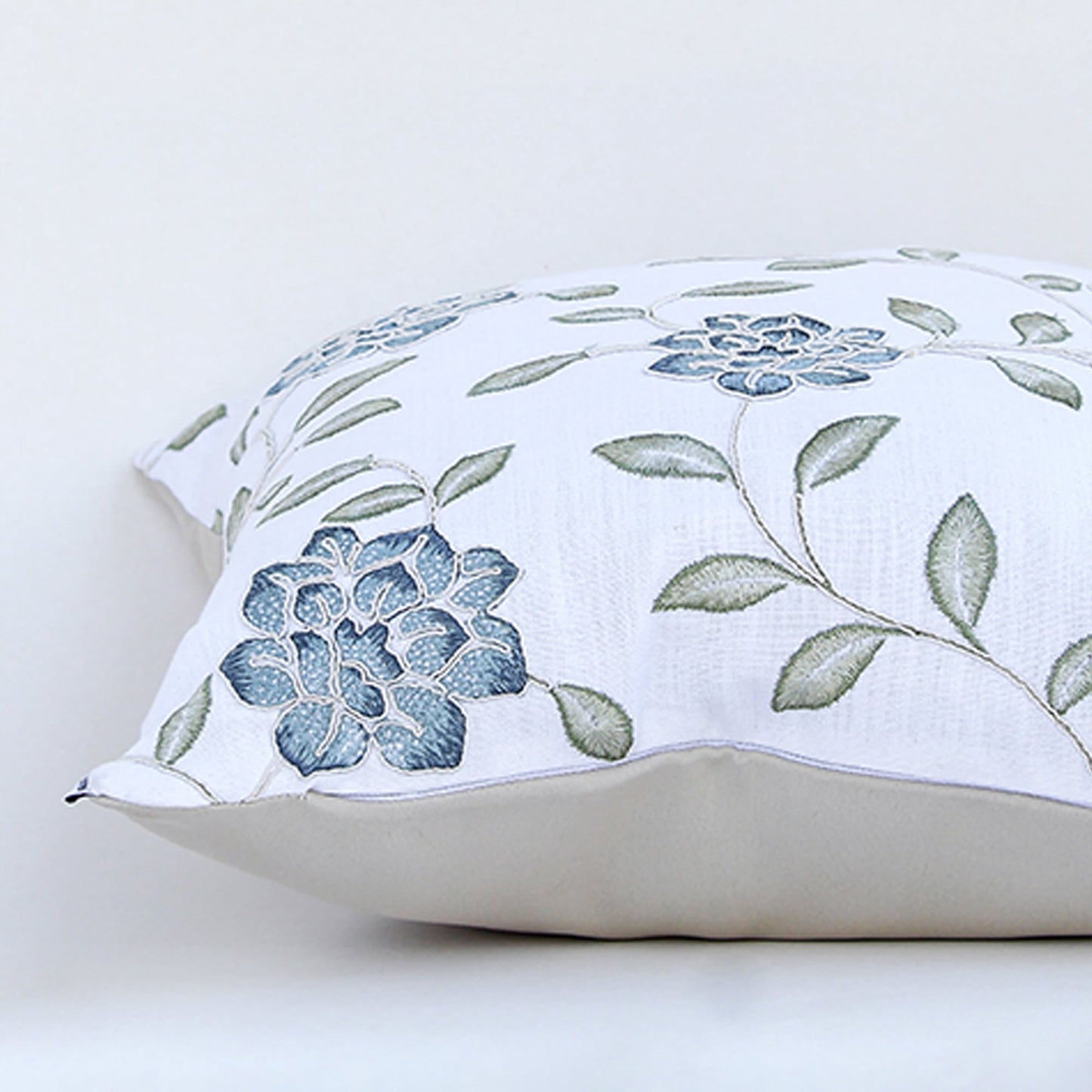 Closeup view of cotton cushion embroidery showing detailed blue floral stitching and soft textured fabric perfect for elegant home decor accents.