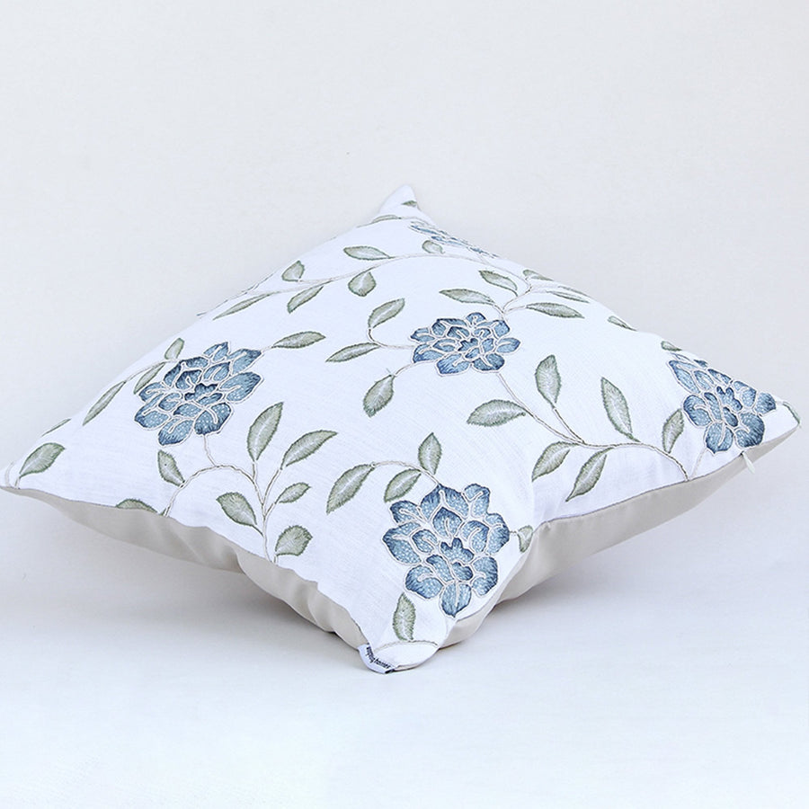 Blue floral embroidered cotton cushion shown on a clean white background showcasing intricate stitched motifs and plush decorative fabric texture.