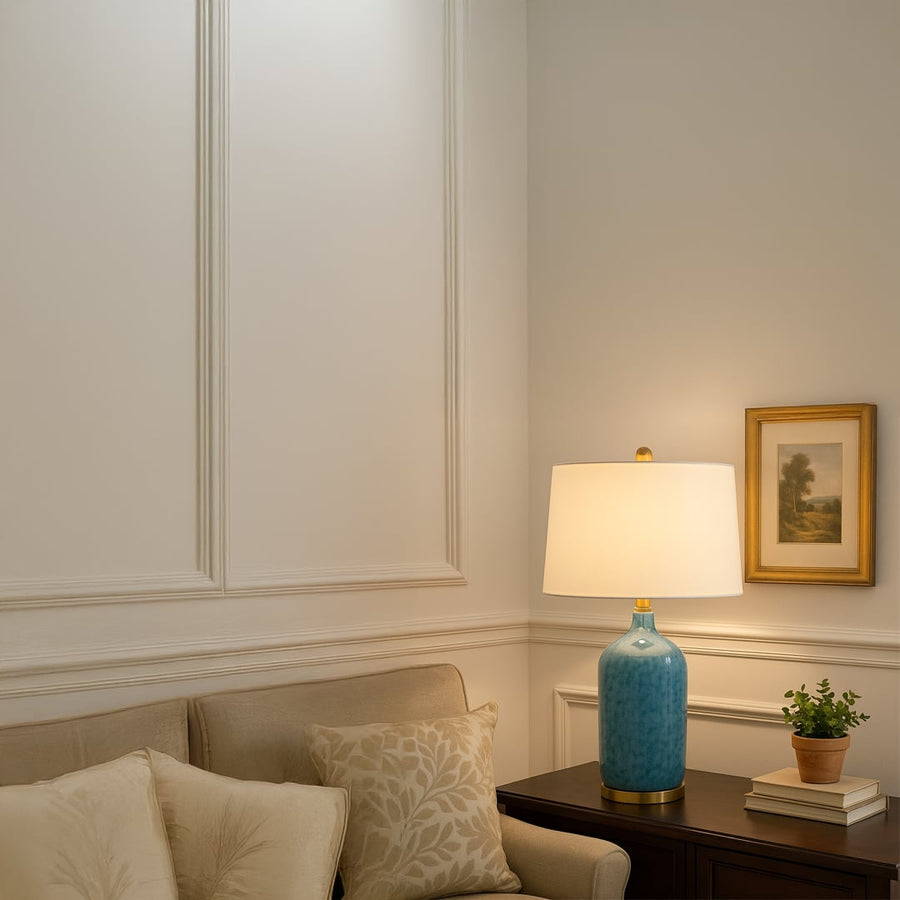 Modern blue ceramic table lamp with gold metal base and white fabric shade adds elegance and a refreshing coastal charm to interiors.