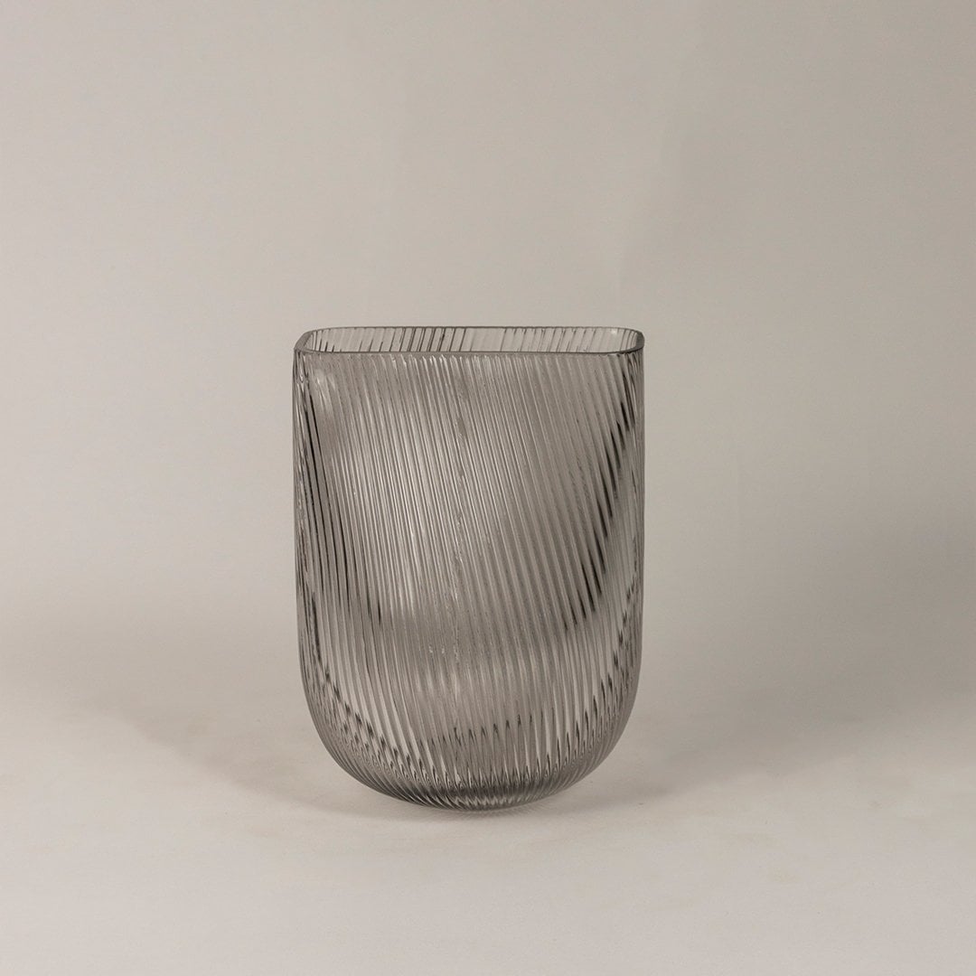 Smoky gray ribbed glass vase with a modern curved design displayed on a plain white background.