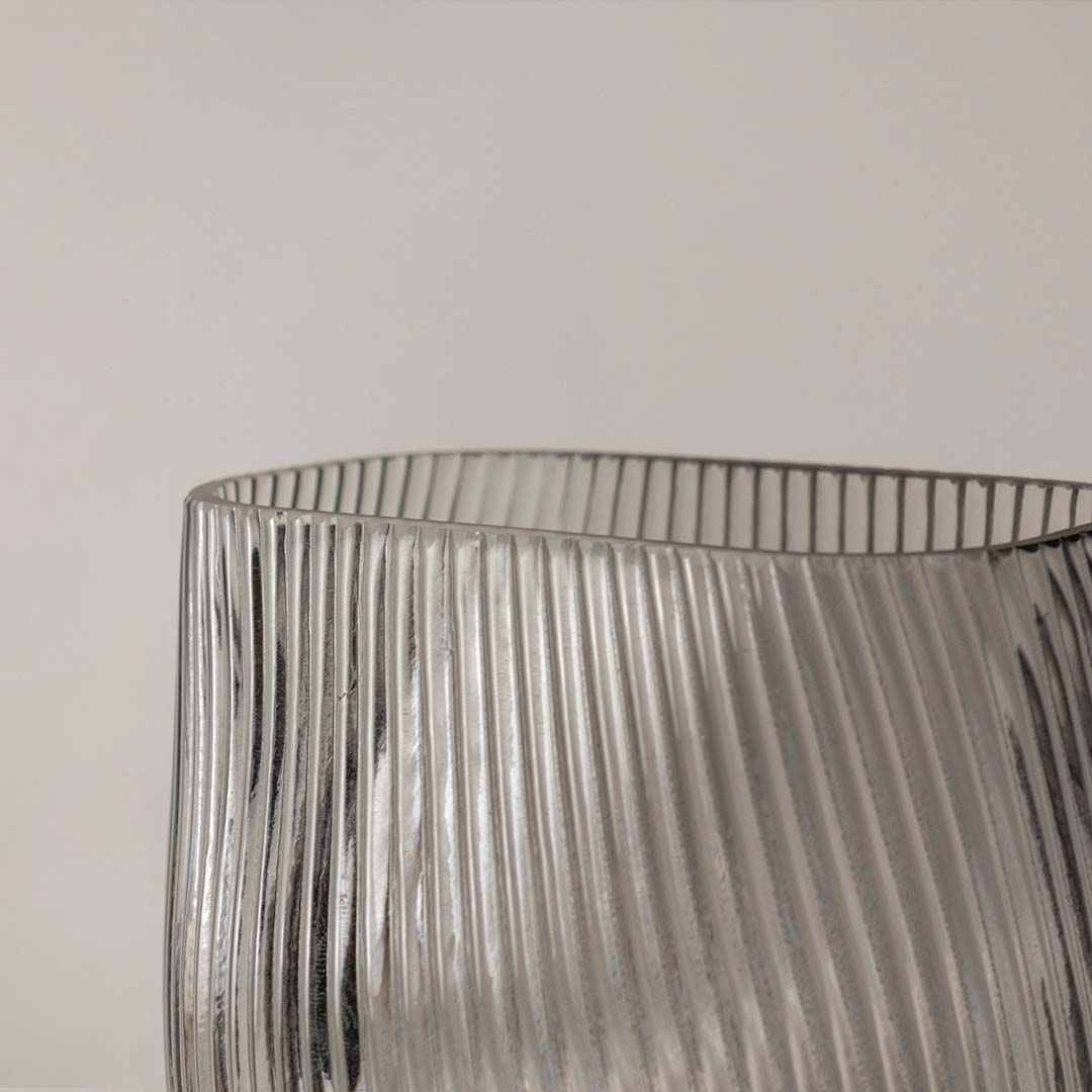 Closeup of smoky gray ribbed glass vase showing fine diagonal ridges and a smooth rounded base.