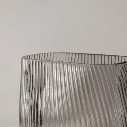 Closeup of smoky gray ribbed glass vase showing fine diagonal ridges and a smooth rounded base.