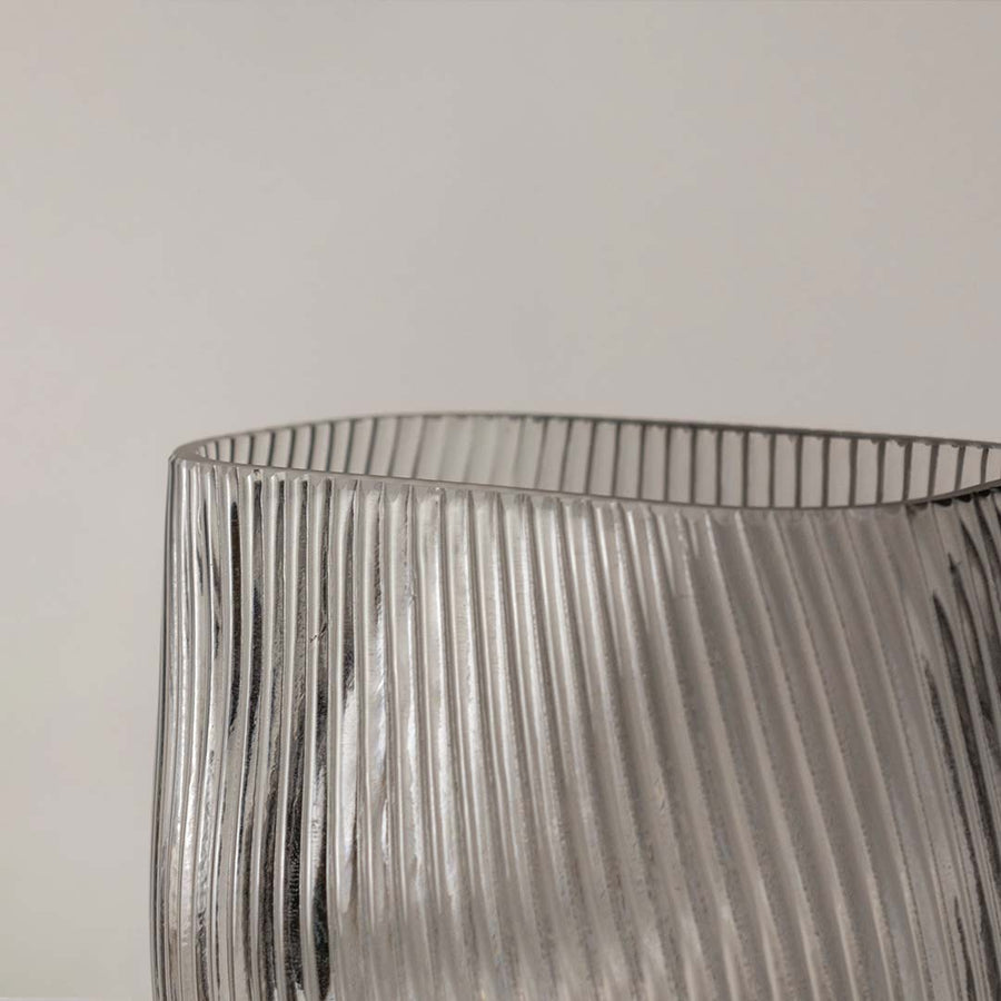 Closeup of smoky gray ribbed glass vase showing fine diagonal ridges and a smooth rounded base.