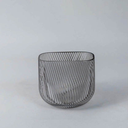 Contemporary smoky gray decorative vase with vertical ribbed pattern and curved form showcased on a clean white backdrop.