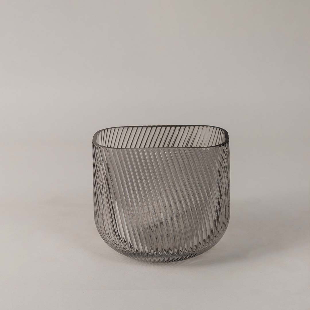 Modern ribbed glass vase in smoky gray tone displayed on a white background emphasizing its sleek and stylish form.