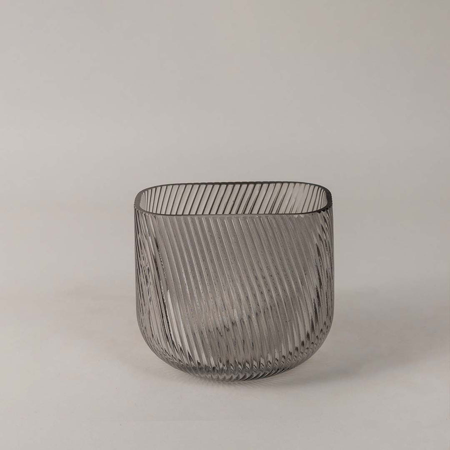 Modern ribbed glass vase in smoky gray tone displayed on a white background emphasizing its sleek and stylish form.