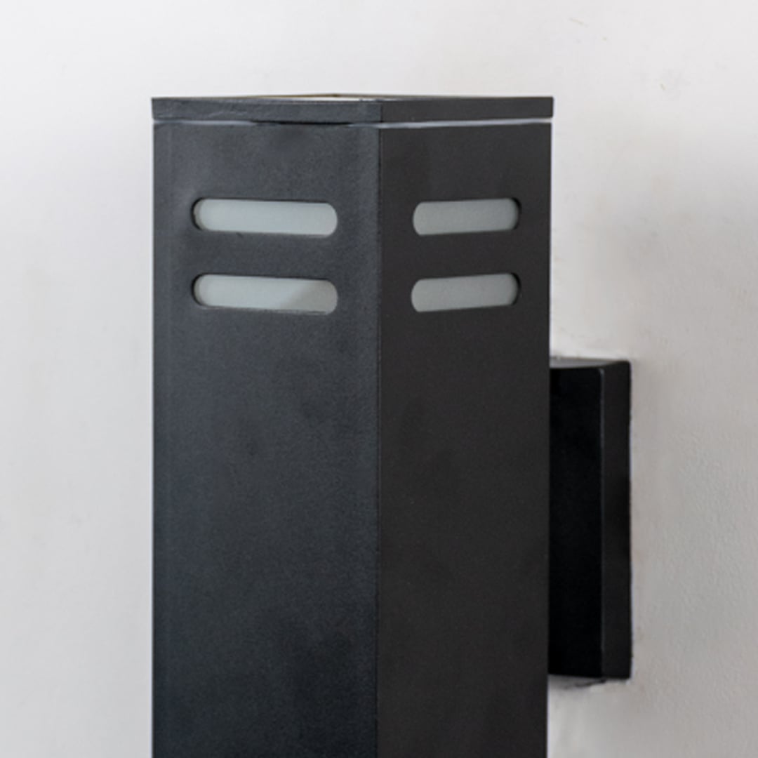 Closeup of black rectangular wall light showing precise metal structure and frosted glass panel detailing.