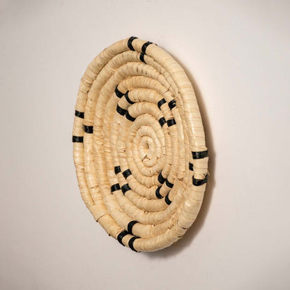 Side profile of the flat woven wall basket showing the thick natural fiber coils and black stitching details on a white surface.