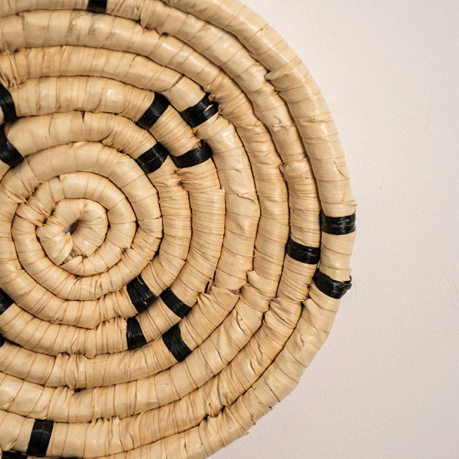 Detailed closeup view of the tight coil weaving and black stitched accents on the natural seagrass wall basket surface quality.