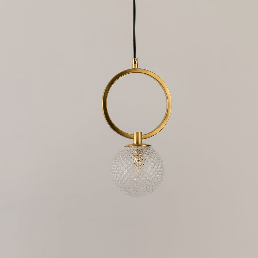 Gold ring pendant light on a white background with the light off highlighting its sculptural modern form and glass detailing.