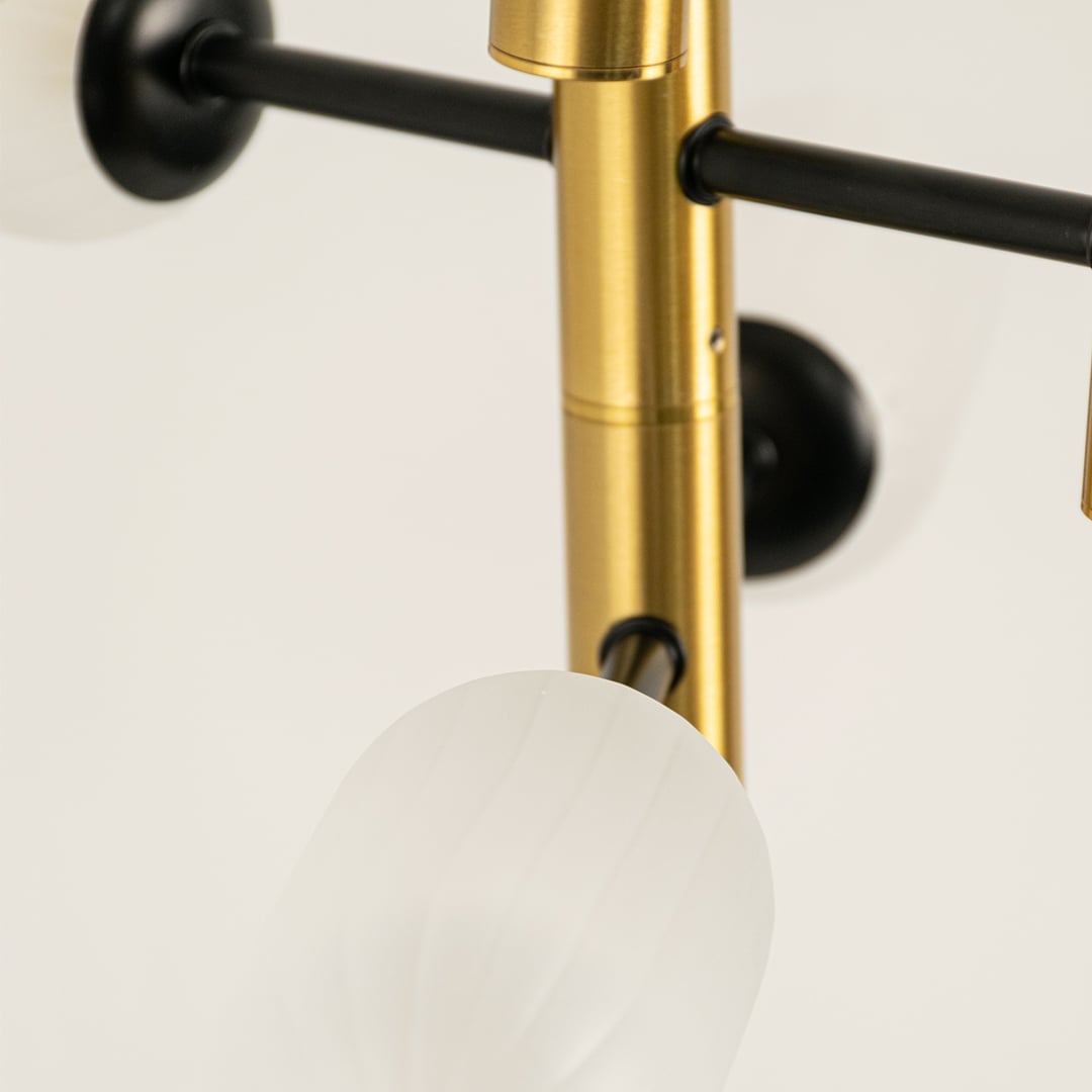 Close view of gold black and white chandelier showing frosted glass detailing metallic finish and morden minimalist craftsmanship.
