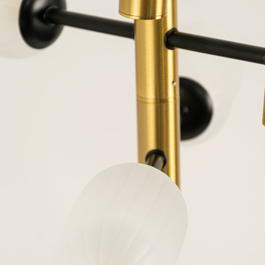 Close view of gold black and white chandelier showing frosted glass detailing metallic finish and morden minimalist craftsmanship.