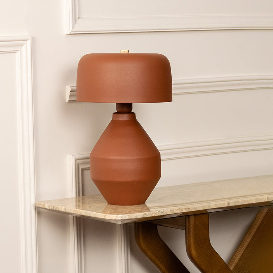 Terracotta table lamp with sculptural ceramic base and matching shade styled on shelf in modern living space.