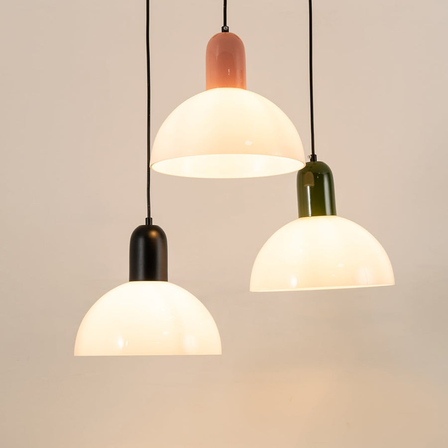 Black white and coral pendant lights creating warm ambient lighting in a contemporary dining room setting.