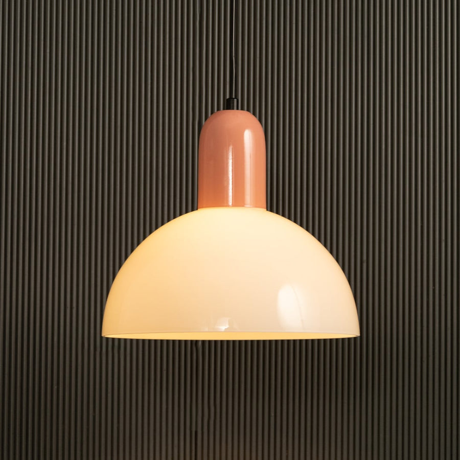 A warm glowing dome pendant light with a soft peach top displayed against a ribbed dark background creating gentle ambient lighting and elegant contemporary décor.