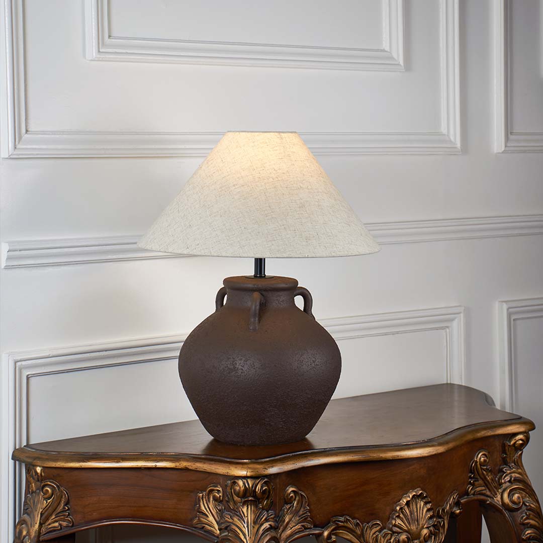 Brown ceramic table lamp with beige linen shade glowing on white background ideal for bedroom lighting table lamp.