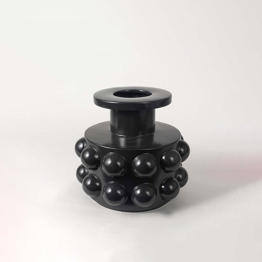 Modern black ceramic vase showcasing bubble-inspired round textures and sculptural cylindrical body on a white backdrop.