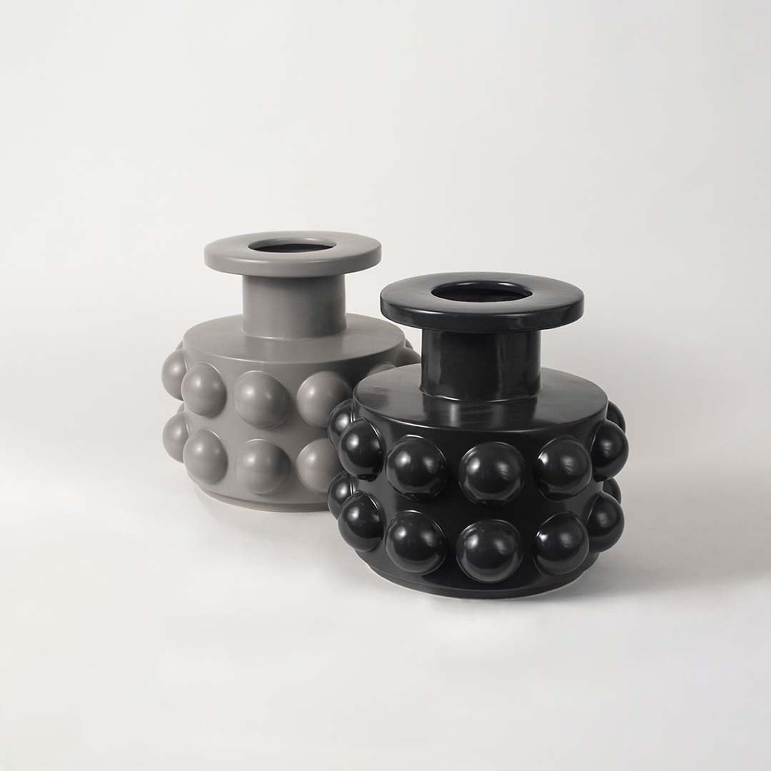 Set of two black ceramic vases with raised circular textures arranged in a modern living space setup.