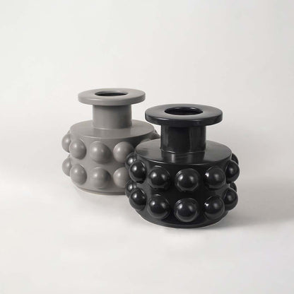 Set of two black ceramic vases with raised circular textures arranged in a modern living space setup.