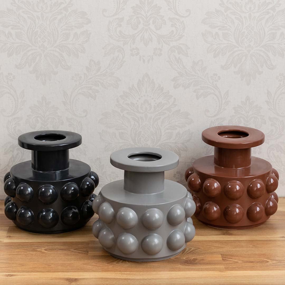 Set of three ceramic vases with spherical design styled with neutral-toned decor and dried floral arrangements.