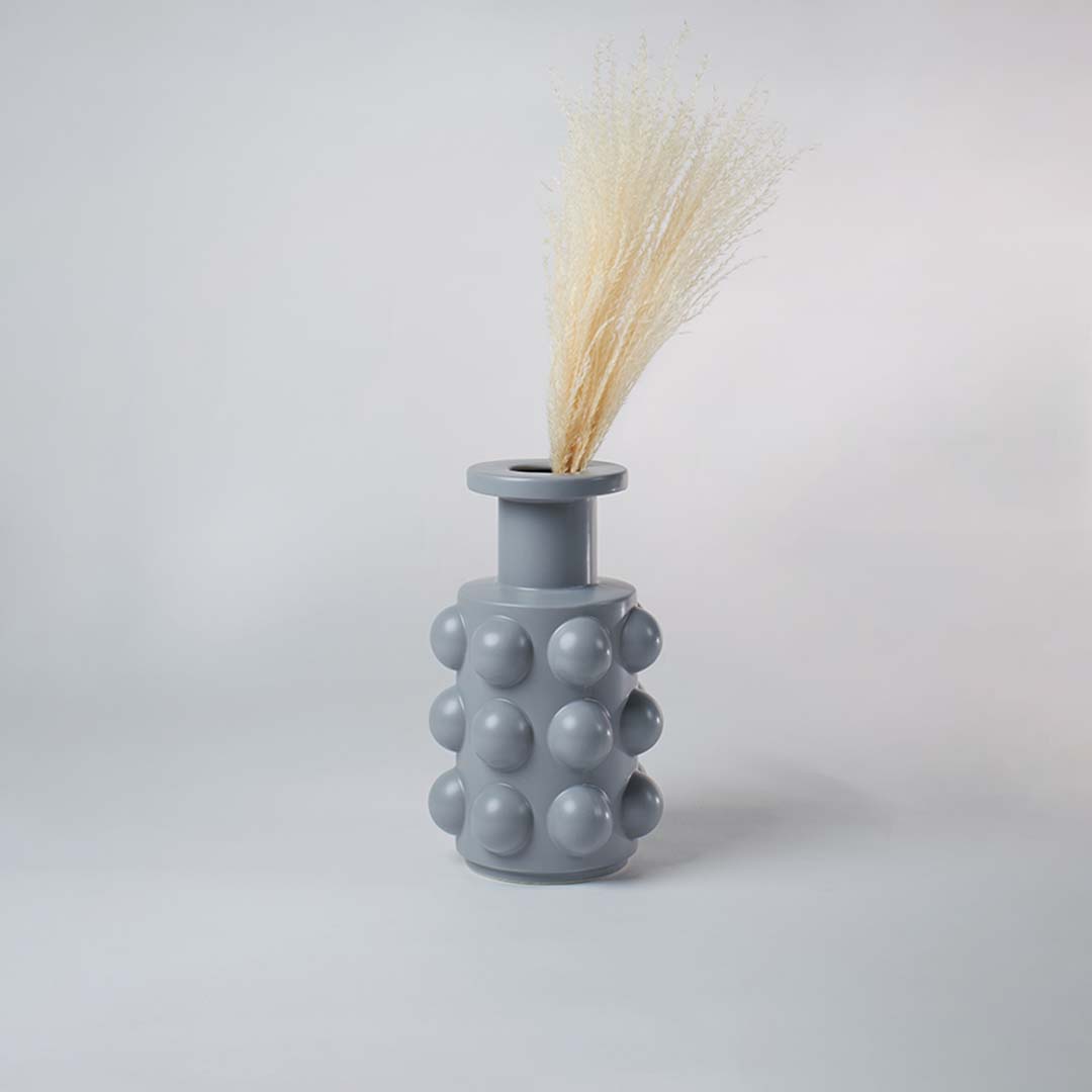 A textured grey decor vase with rounded raised elements shown in a simple styled space highlighting its modern artistic design for home styling.