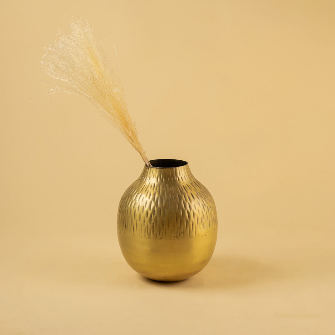 Textured hammered gold round vase with dried grass for artistic modern home decor and tabletop display styling.