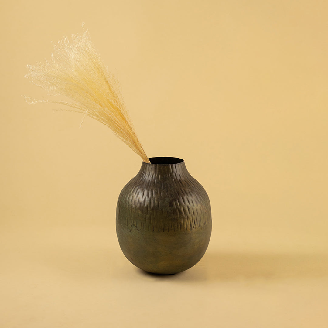 Textured dark bronze round vase with dried grass for artistic home decor and contemporary interior styling.