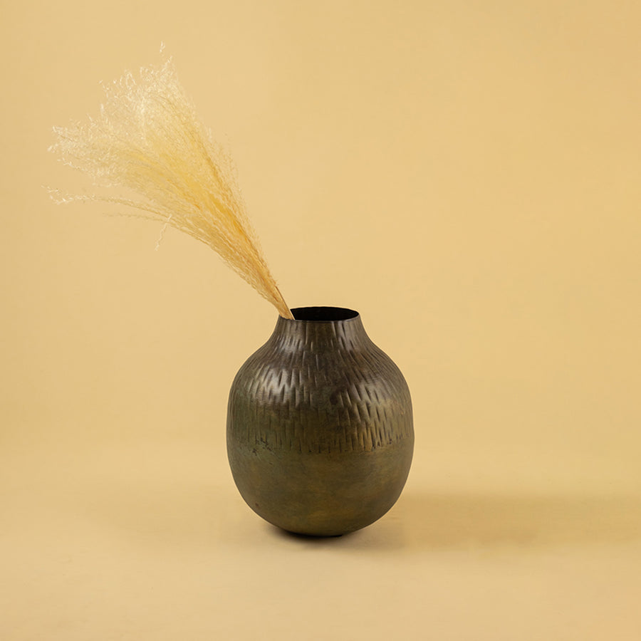 Textured dark bronze round vase with dried grass for artistic home decor and contemporary interior styling.