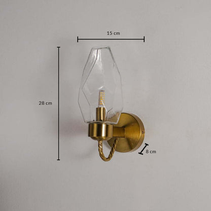 Wall lamp with geometric clear glass shade and gold finish base shown with size 28 cm height 15 cm width and 8 cm depth.