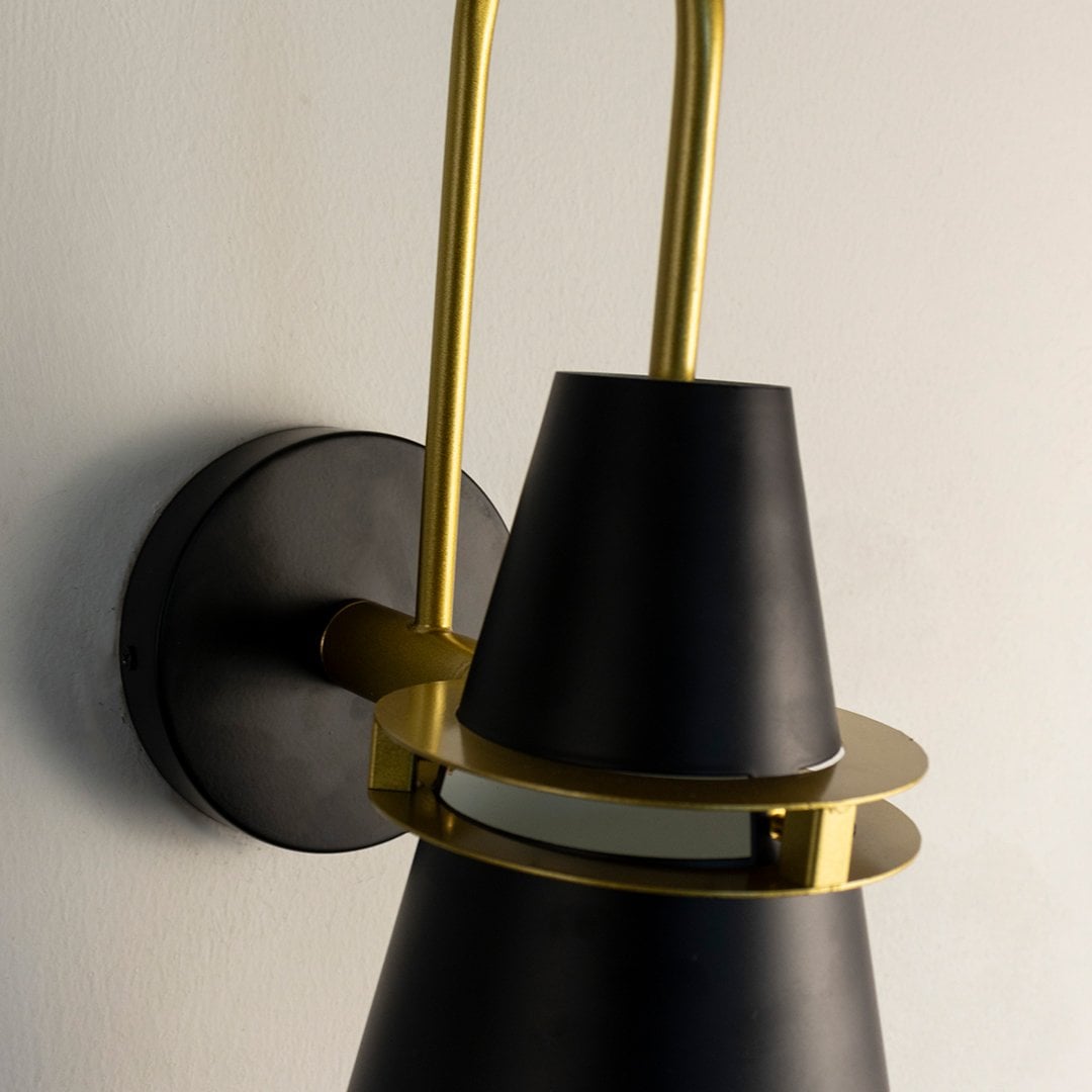 Closeup of black and gold conical wall lamp highlighting smooth matte finish and refined metallic craftsmanship.